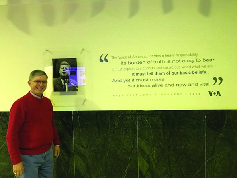 A person standing in front of a poster

Description automatically generated