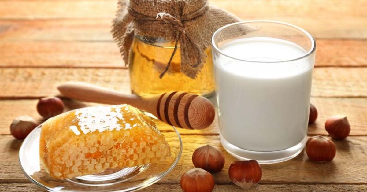 A wooden table displays honey, milk, and nuts, illustrating the benefits of milk and honey for health and wellness.