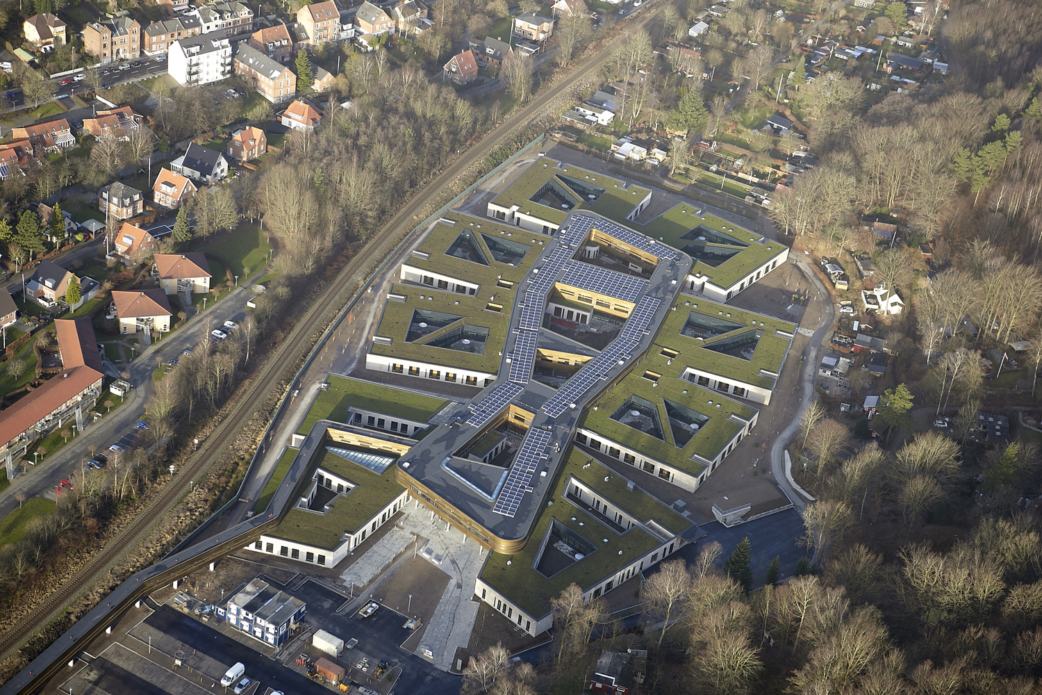 An aerial view reveals a hospital design building with a green roof shaped like a honeycomb.