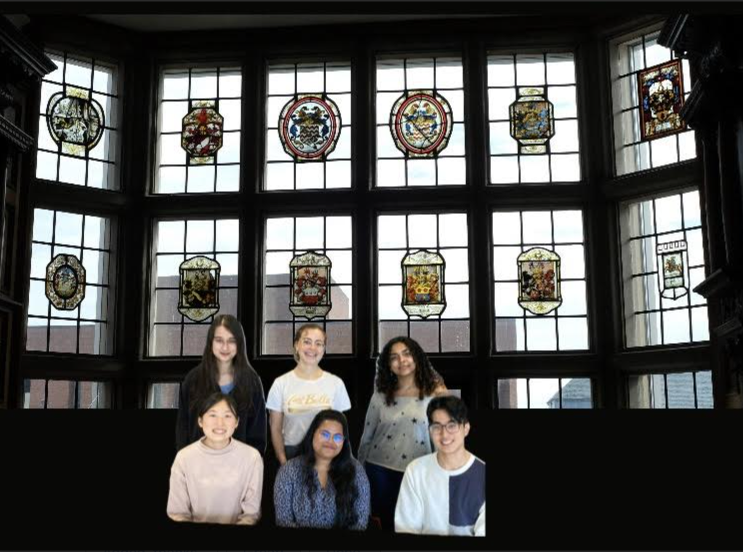 Six young people pose in front of a large, ornate window with stained glass panels.