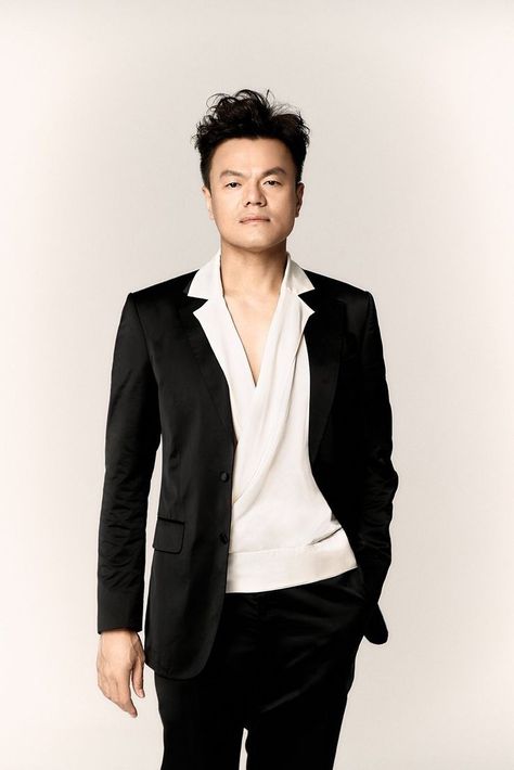 This contains an picture of J.Y. Park  on a black jacket and a white shirt wearing a black trouser 