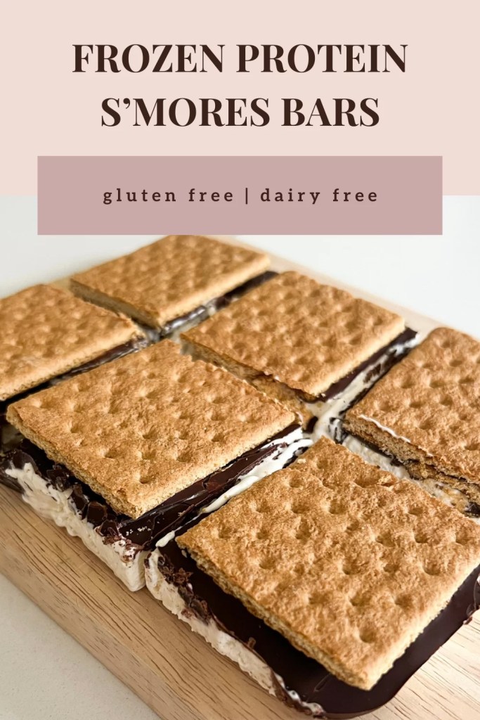 These frozen protein s'mores bars are gluten free, dairy free, high protein, can be low sugar, the perfect summer dessert. On a cutting board are the s'mores bars before cutting. Three golden brown graham crackers with hardened rich chocolate showing through the cracks between on the sides. A creamy, thick white protein whip shows spilling over the sides. Like ice cream sandwiches and ready to eat. One is cut into a square and showing side angle of the thick whip layer, chocolate crunch, and cracker 