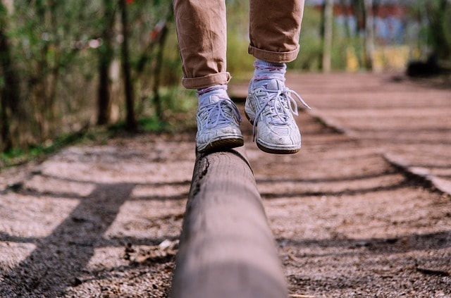 A man keeps balance with shoes on a railroad track to show concept of balancing digital usage