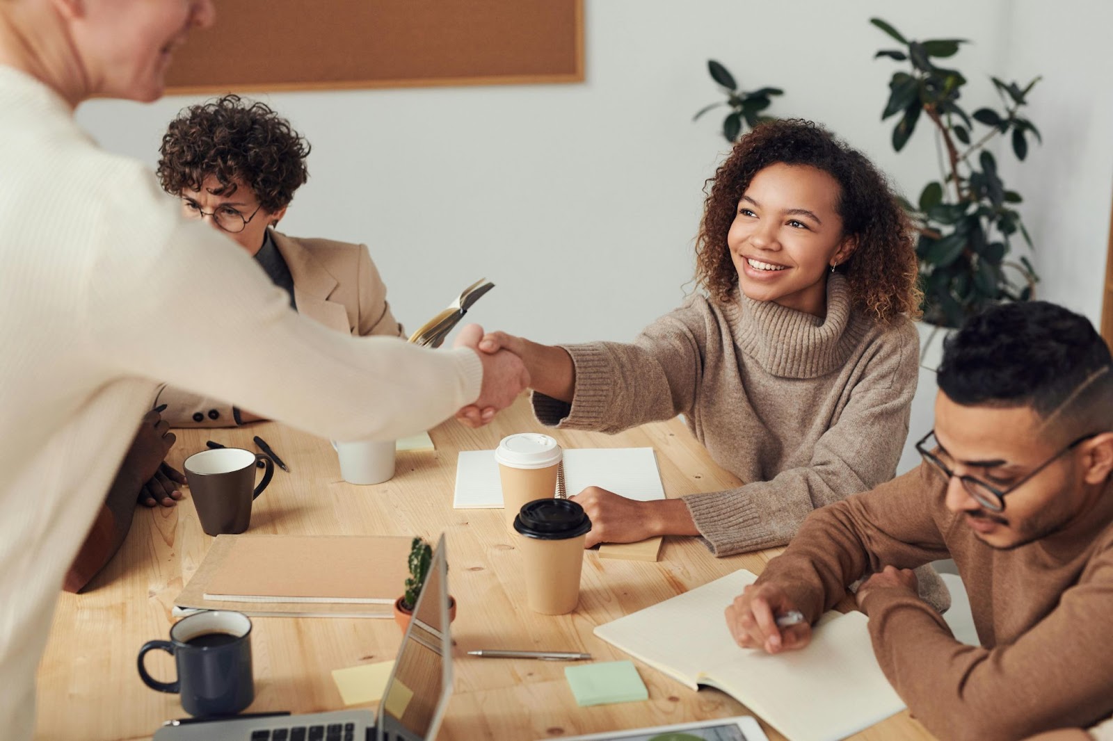 2 people shaking hands over a office table.