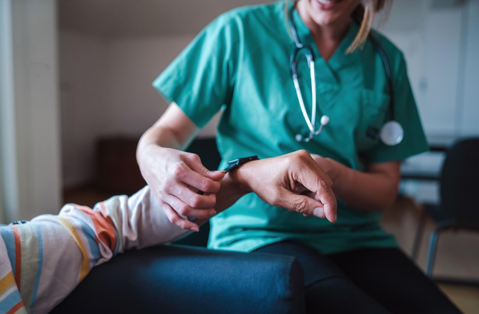 A nurse helps a senior put on a smartwatch that will help monitor their health while living in assisted living