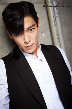 This contains an image of T.O.P putting on a black and white cloth
