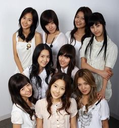 This contain a group of Girls' Generation standing next to each other in front of a white wall