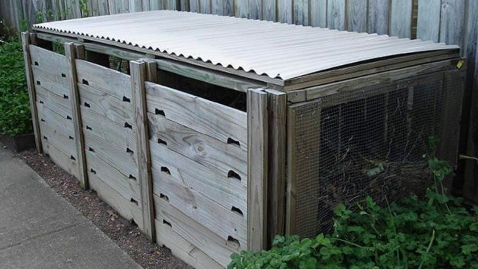 Example of a DIY outdoor compost bin set up featuring 3 separated bins, cover, and mesh sides to increase airflow and maximize microbial activity