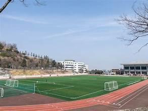 A sports field with a white building and trees

AI-generated content may be incorrect.