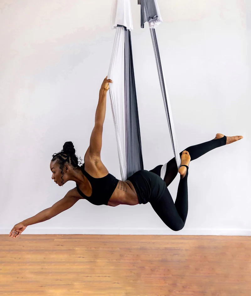 woman doing aerial yoga in what appears to be a flying pose