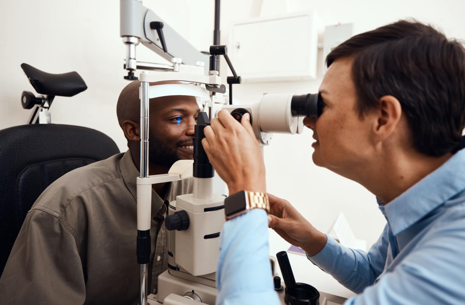 Smiling patient getting their eyes checked by an optometrist to monitor for worsening myopia.