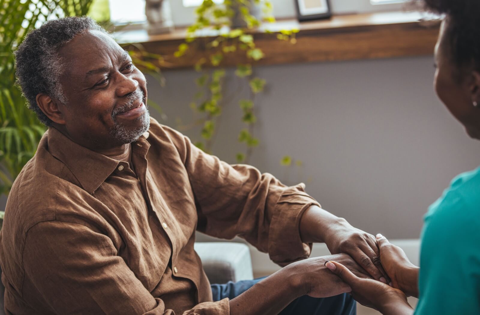 An older adult holding hands with a loved one and smiling while discussing a move into a senior living community.