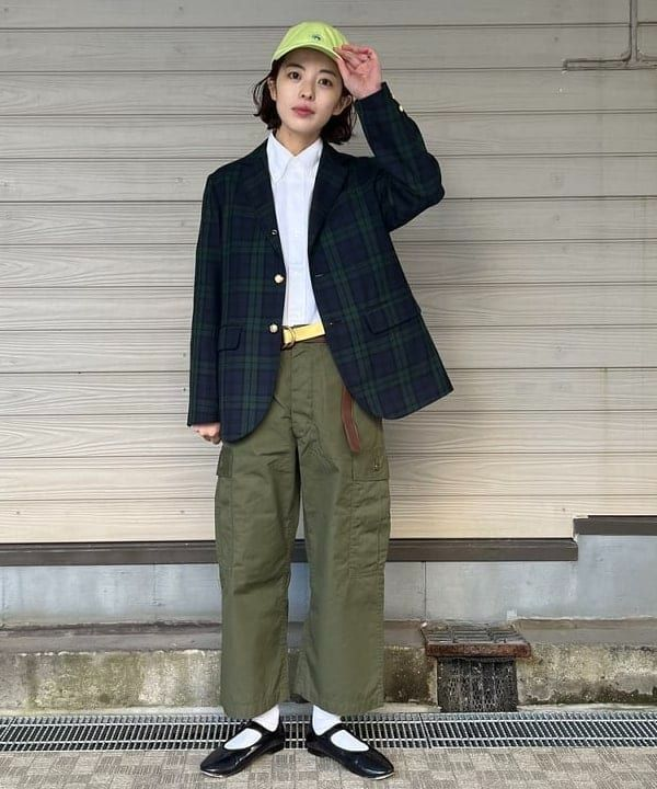 wanita memakai kemeja putih, blazer navy hijau, celana hijau, topi, dan sepatu hitam