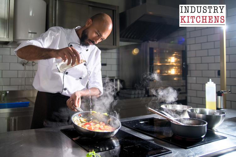 A chef expertly prepares a meal using an induction cooker in a bustling commercial kitchen environment.