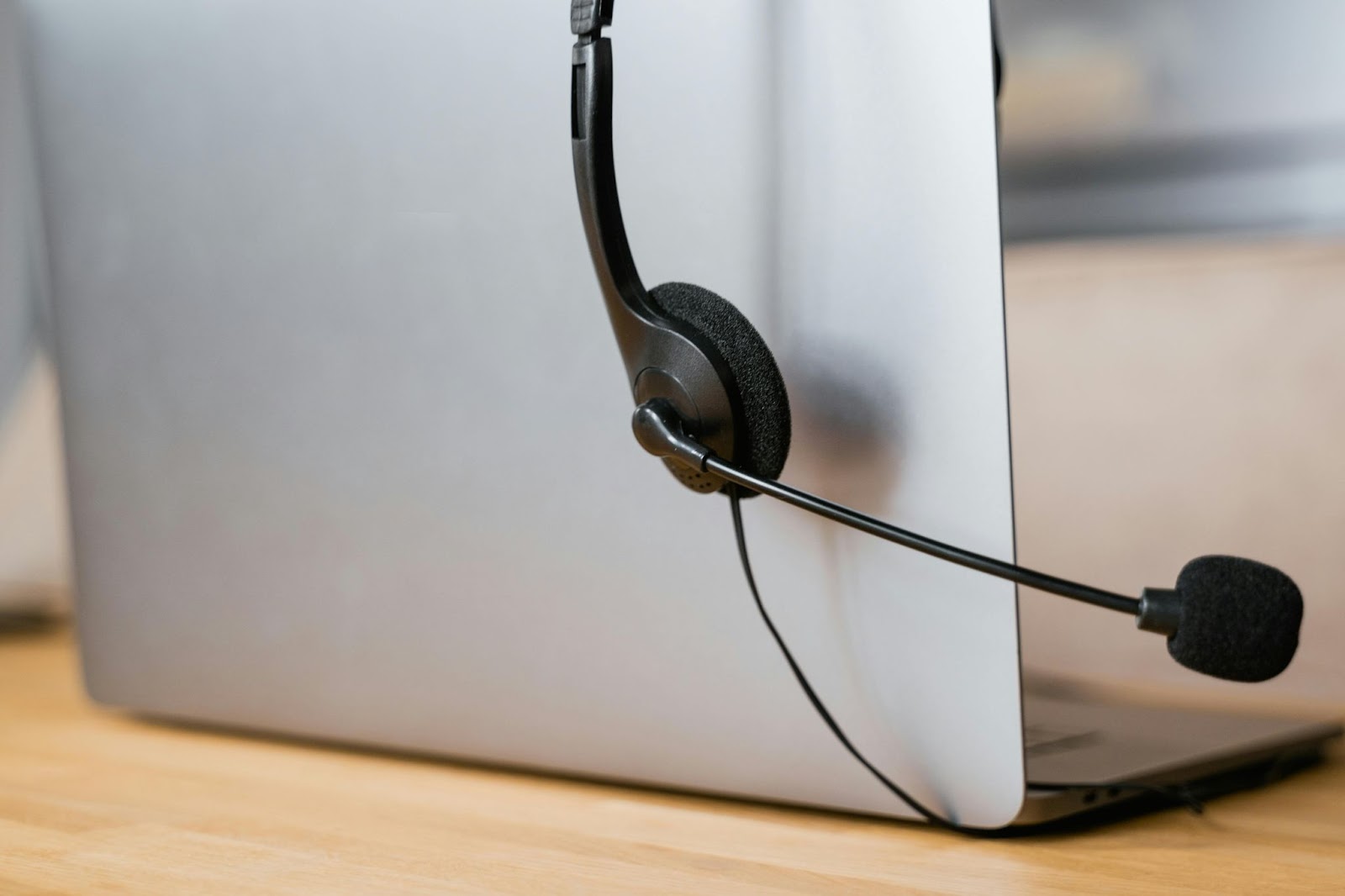 Laptop with a microphone headset hanging on it.