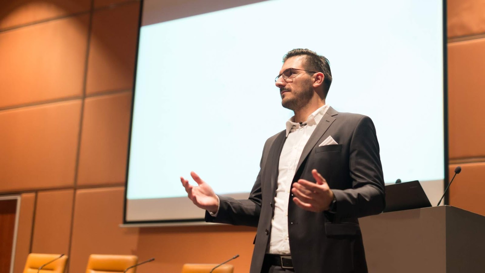 homem de terno apresentando conteúdo em uma palestra corporativa.