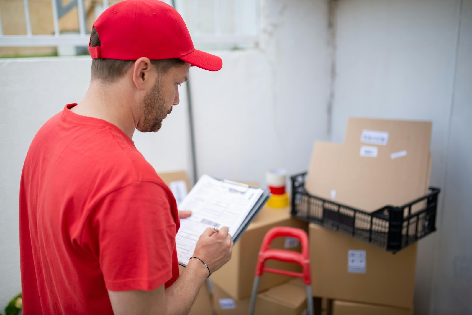 Hombre haciendo un recuento de cajas frente a él mientras rellena una guía, destacando la optimización de rutas, trazabilidad y gestión de transporte (TMS).