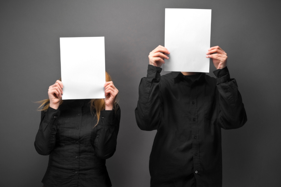 A couple of people holding up paper in front of their faces

Description automatically generated