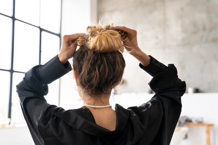 A woman styling her hair by making a bun