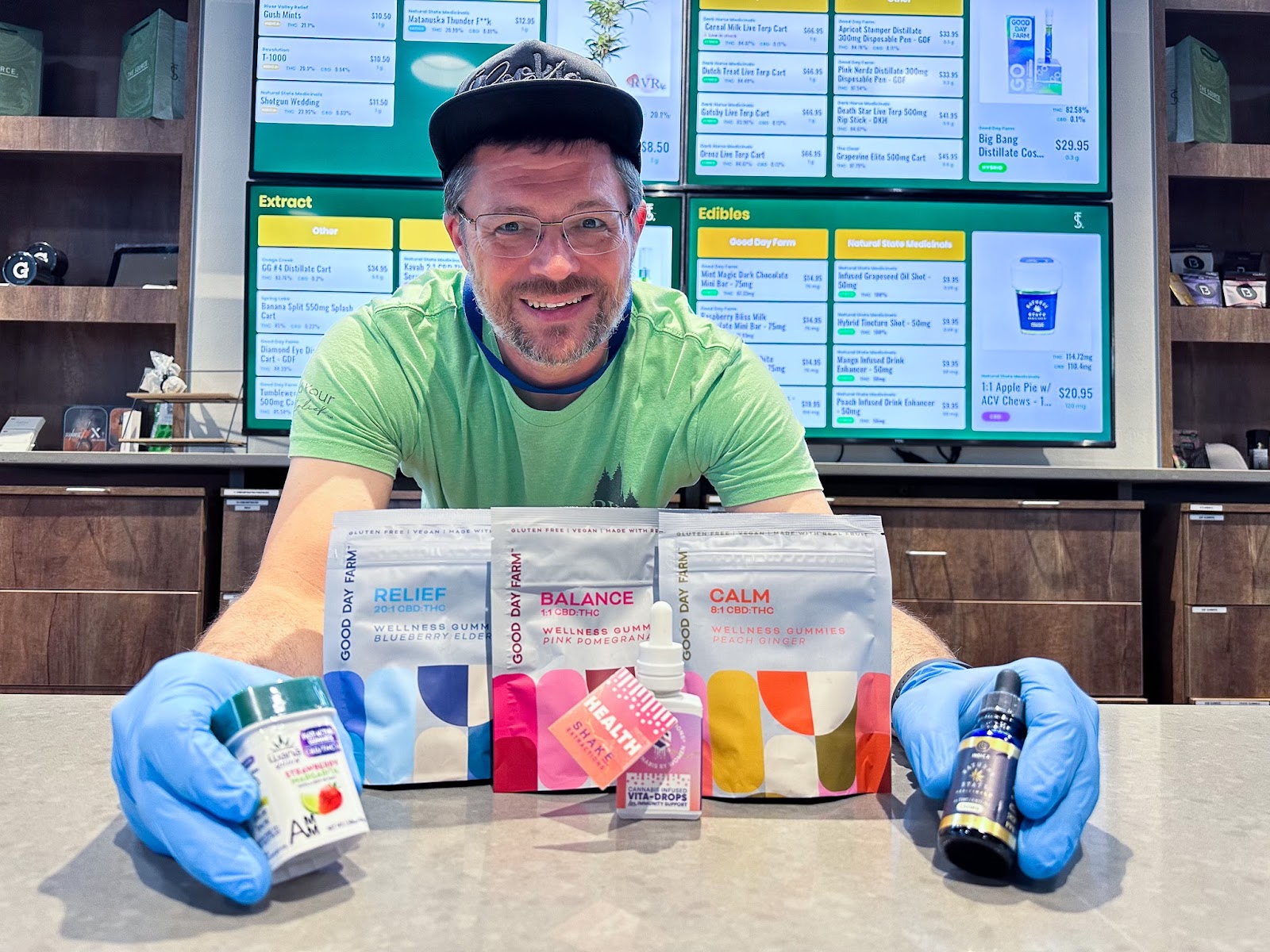 Shaun Forrester, budtender at The Source cannabis dispensary in Rogers, Arkansas displays a collection of cannabis products that contain CBD, including Good Day Farms Relief 20:1, Balance 1:1, and Calm 8:1 gummies, WANA Quick Acting 1:1 Strawberry Margarita gummies, and tinctures by Shake Extractions and Natural State Medicinals.