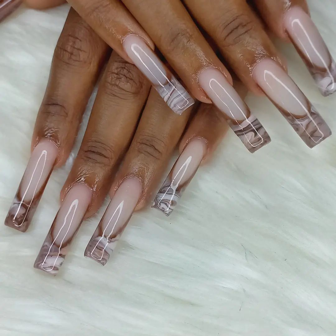 Long, clear acrylic nails with a nude base and square tips on fingers against a white background.