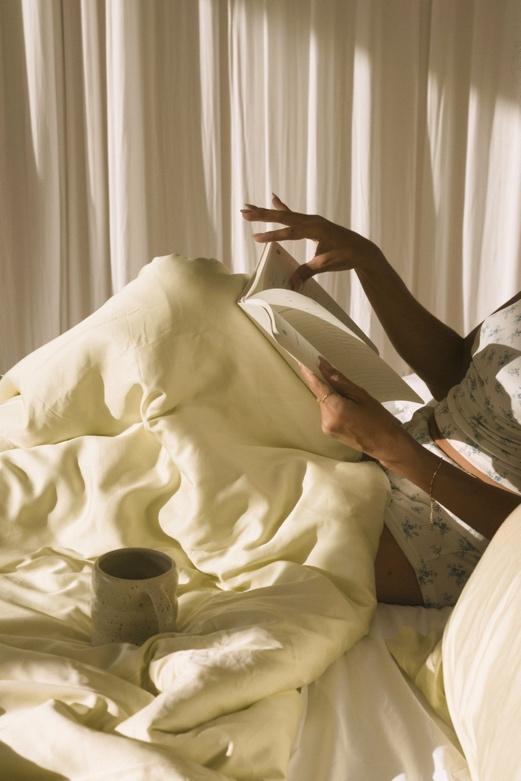A person lying in bed with a cup of coffeeDescription automatically generated