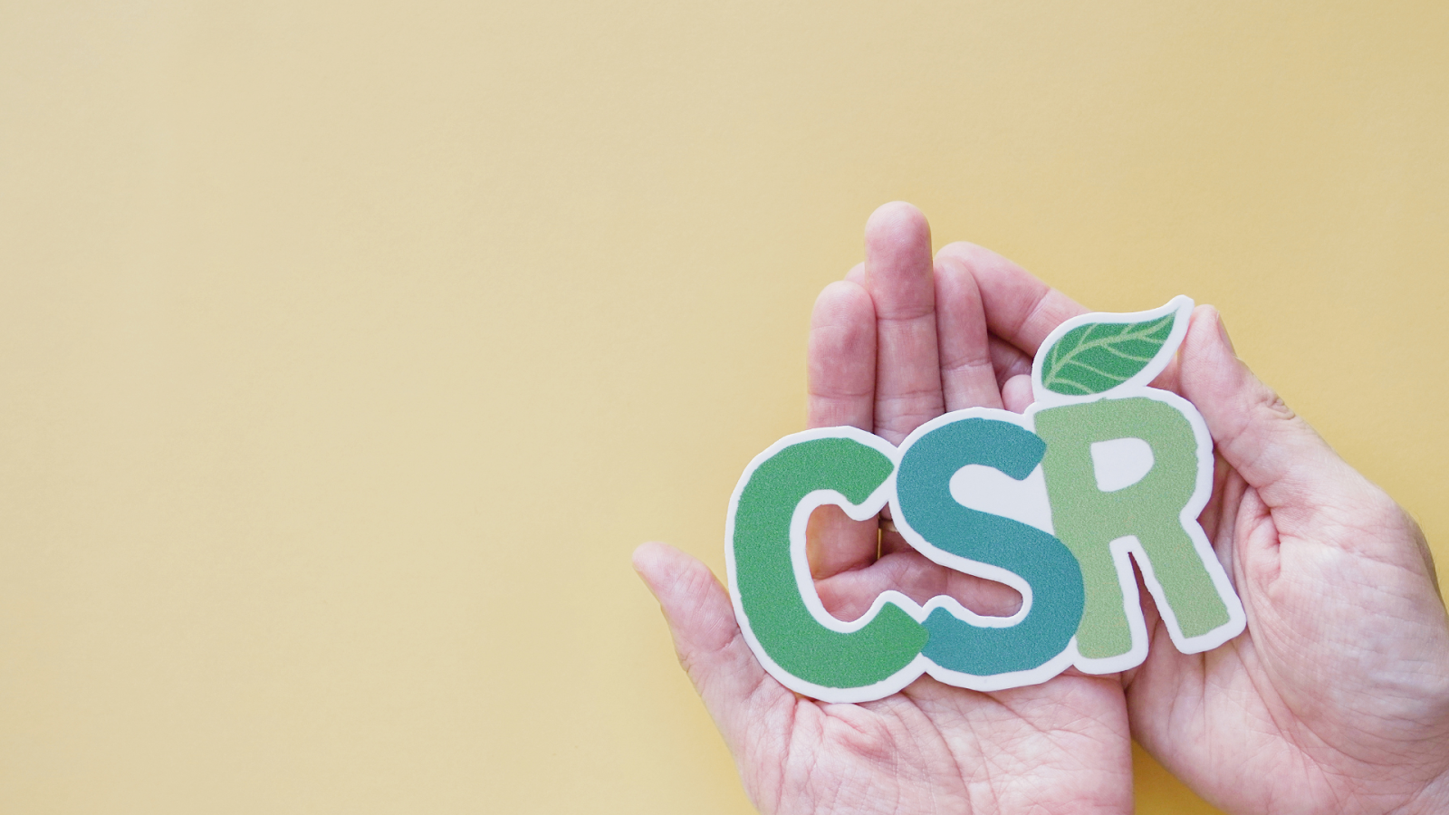 Hands holding the letters "CSR" with a green leaf, symbolising the concept of Corporate Social Responsibility and its integration into business strategies in Singapore.