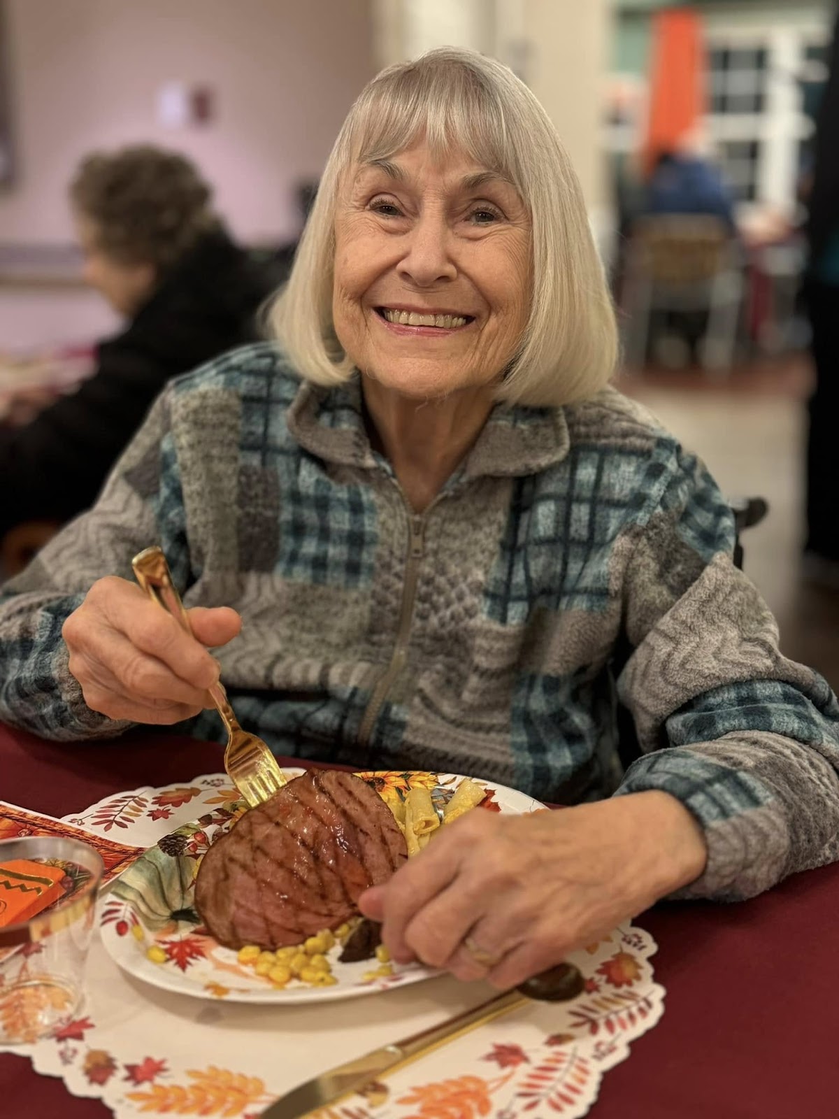 A picture of an assisted living resident eating a steak dinner and smiling