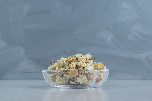 Dried chamomile flowers in glass bowl.  