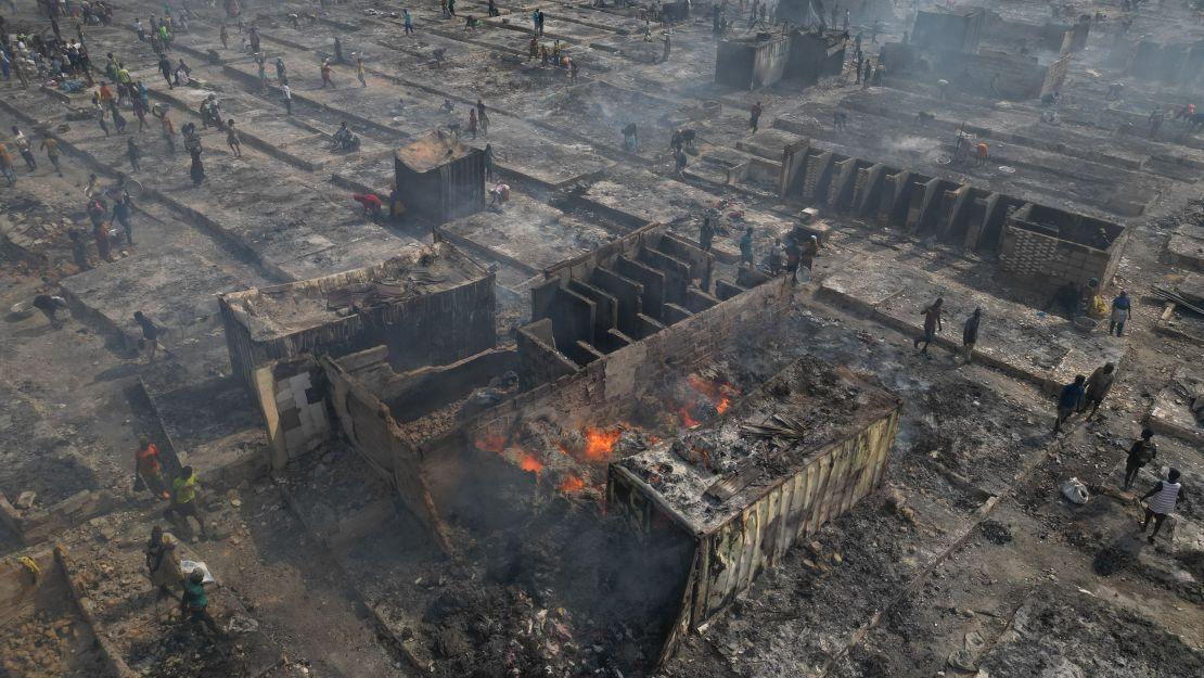 TOPSHOT - This aerial view shows people trying to salvage items from the burned down secondhand clothing market at Kantamanto in Accra, Ghana, on January 2, 2025. The fire at the Kantamanto market began in the early morning hours, destroying a large part of the area and displacing thousands of traders. (Photo by Nipah Dennis / AFP) (Photo by NIPAH DENNIS/AFP via Getty Images)