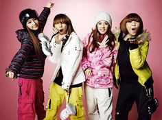 This contain 2NE1standing next to each other in front of a pink background 