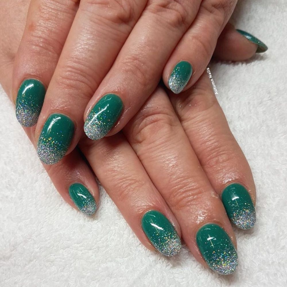 Close up of hands with Christmas Green Nails having  Green Glitter French Ombre