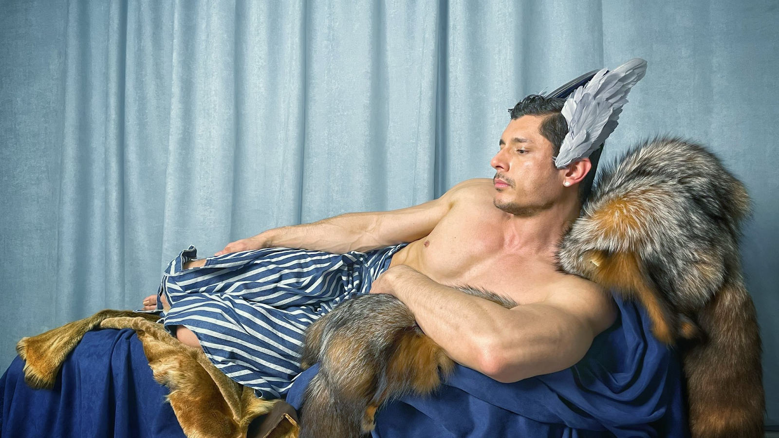 Rocky Vallarta posing against fur on clothed chair 