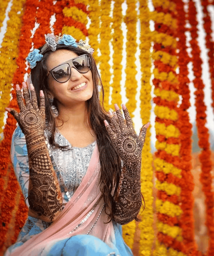 Mehndi photoshoot of a bride smiling and showing her mehndi