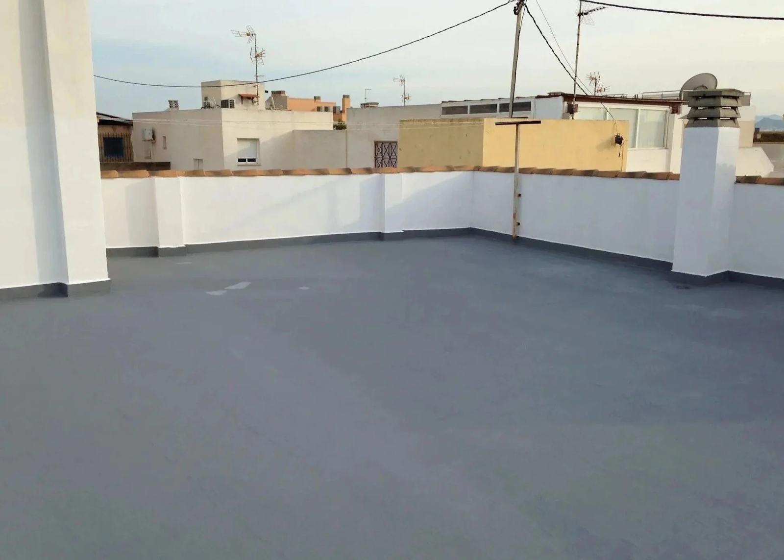 A commercial rooftop with white parapets is coated in the Acriflex Pro waterproofing system