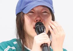 This contains an image of  Min Hee Jin holding a mic on her hand 

