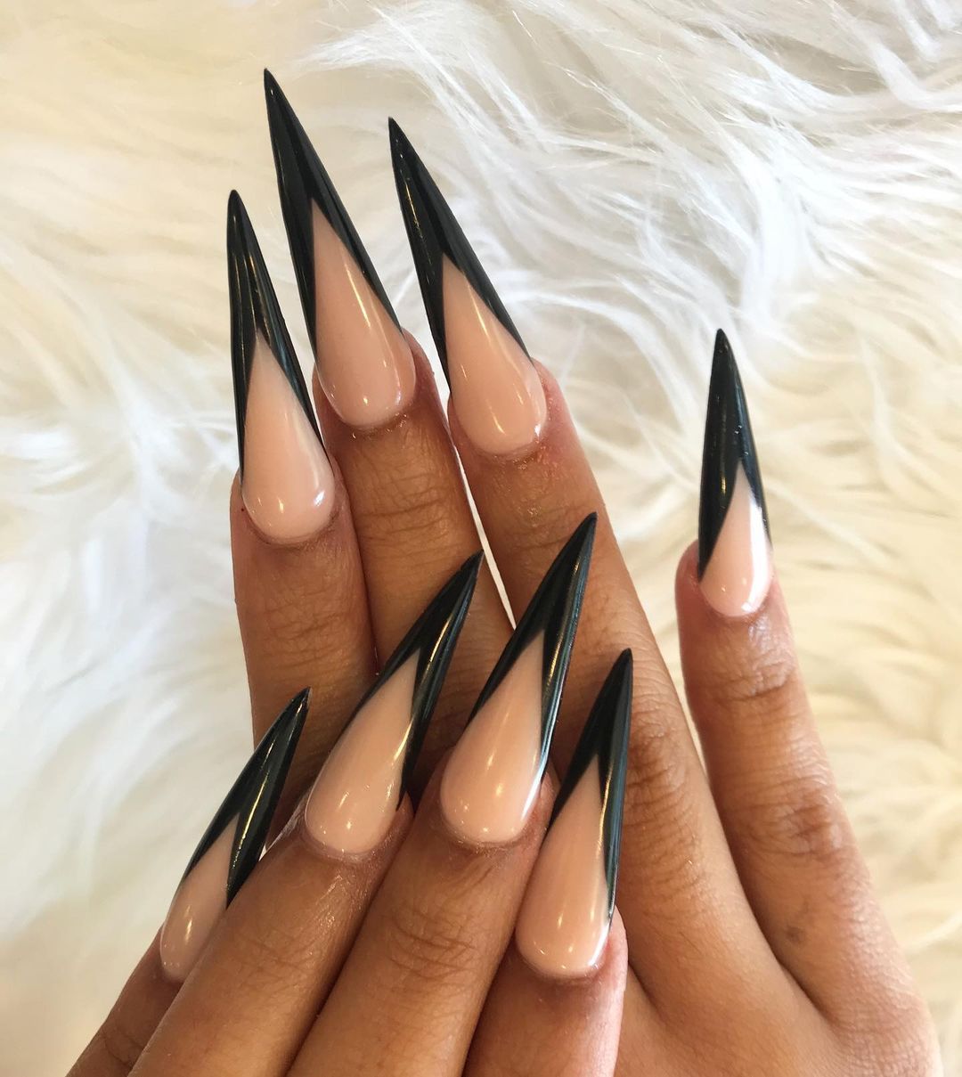 Close-up of a person's hands with black nails having Long, Sharp Stiletto Designs