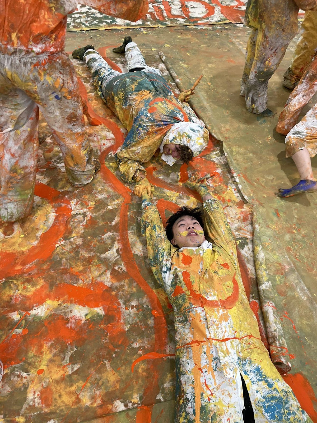 A group of people covered in paint lying on the ground

Description automatically generated