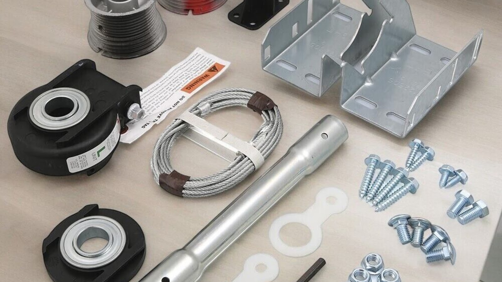 A set of essential garage door replacement parts, such as cables, rollers, and brackets.