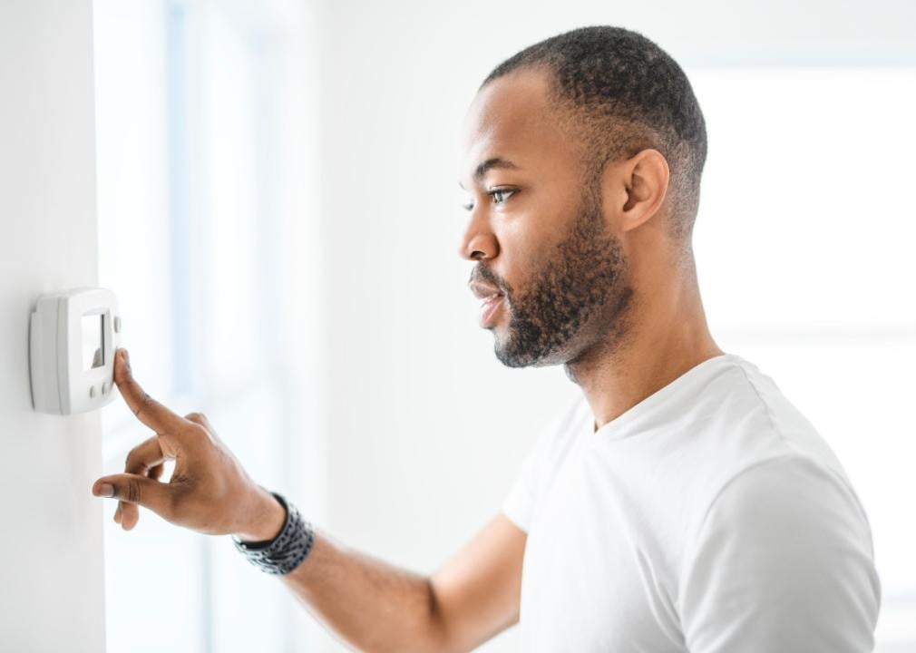 A man adjusting a thermostat.