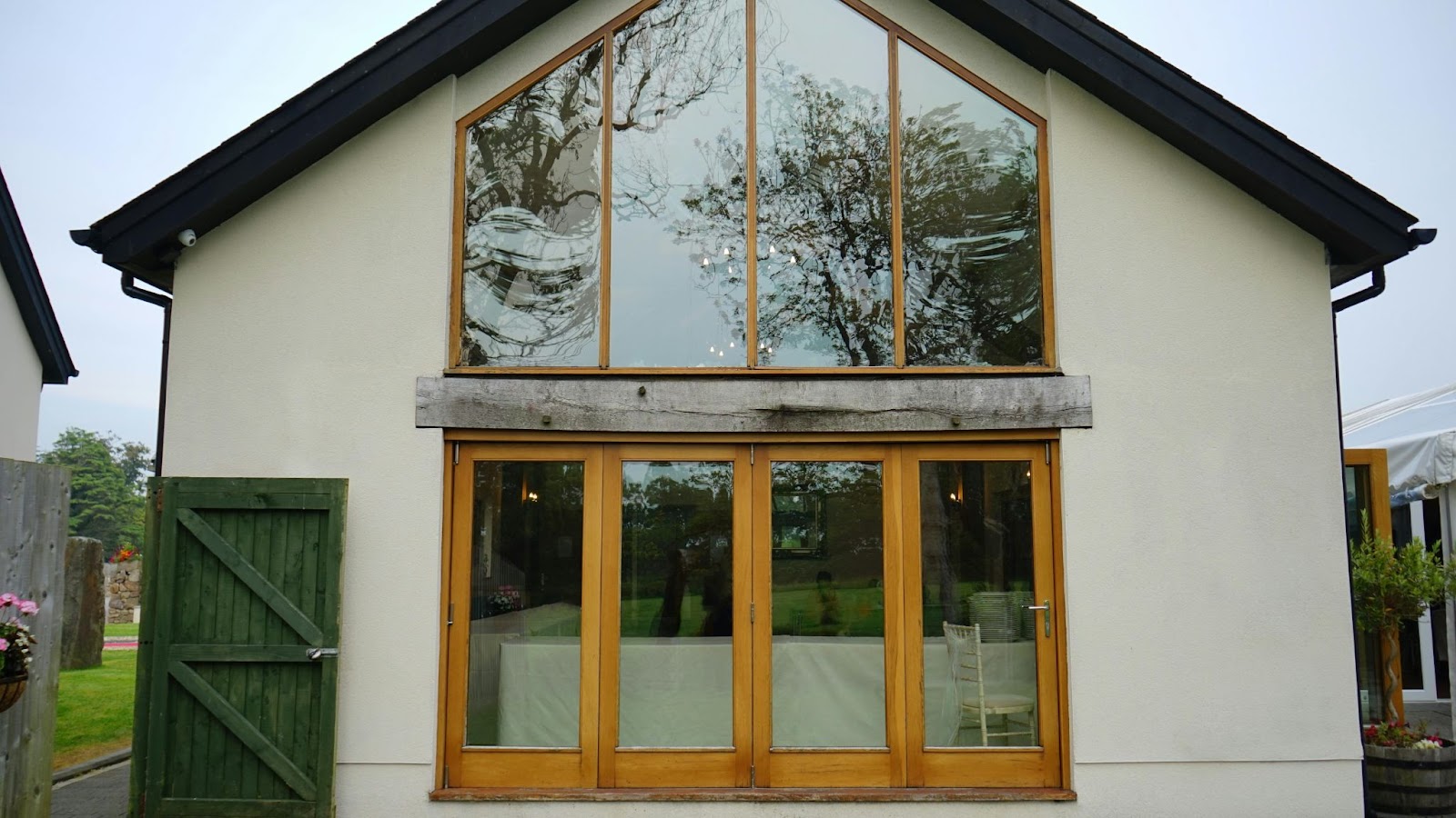 A charming shome featuring several large windows and a striking green door, blending modern design with natural light for a warm and inviting atmosphere.