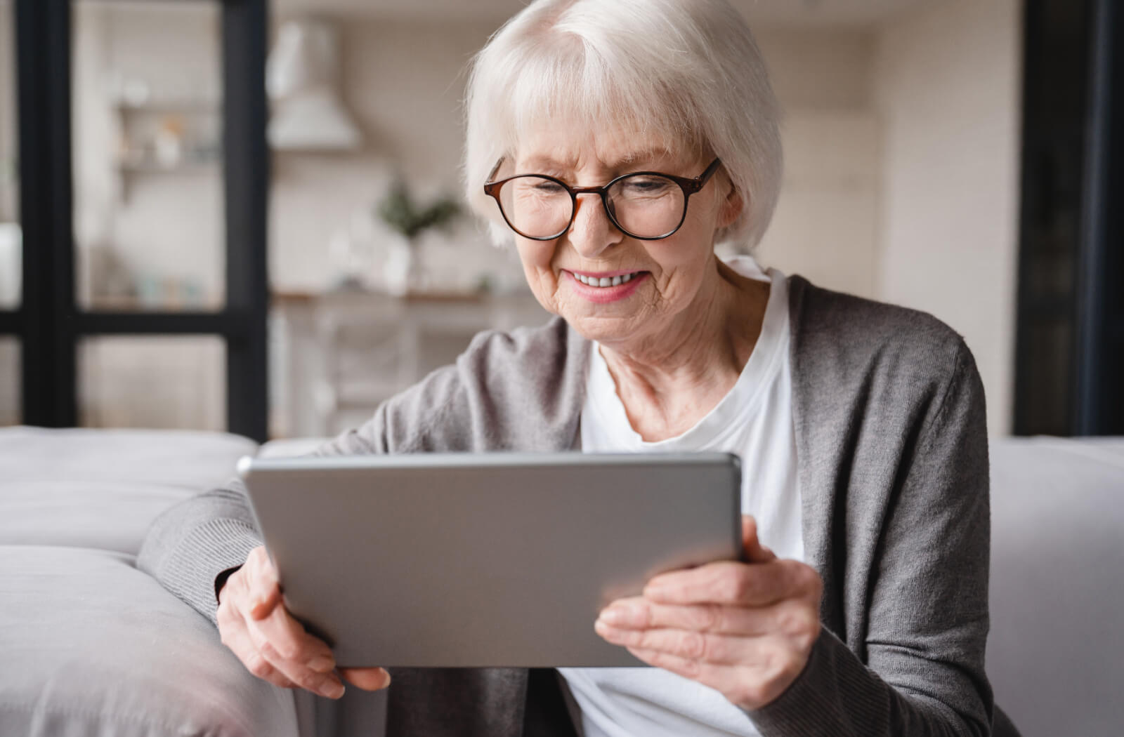 An older adult smiling while looking through their iPad and playing a free game.