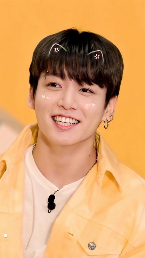  Jungkook BTS on a white polo and a yellow jacket and he is similing