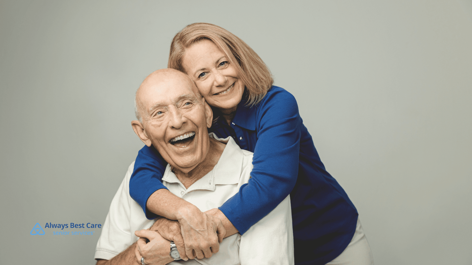 This image depicts an adult woman hugging her senior father