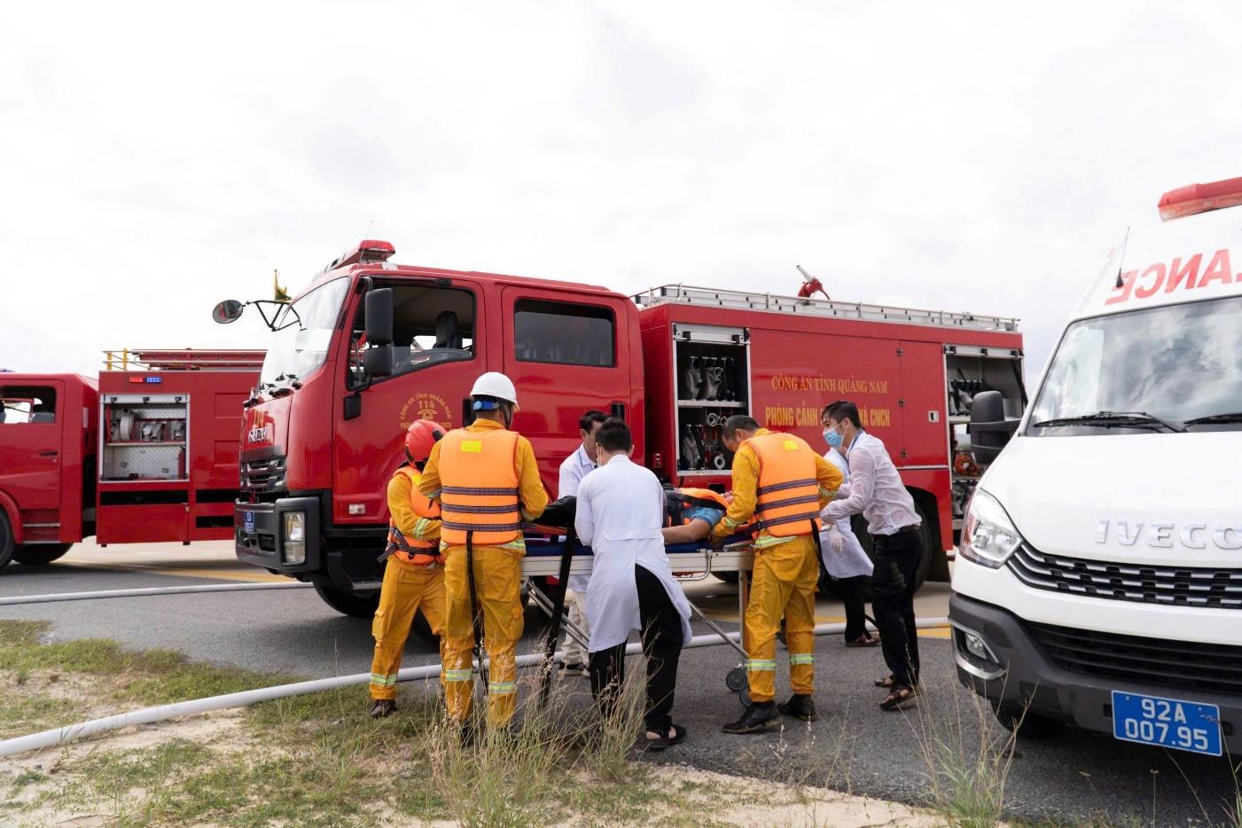 A group of people in orange uniforms and white coats standing next to a red truckDescription automatically generated