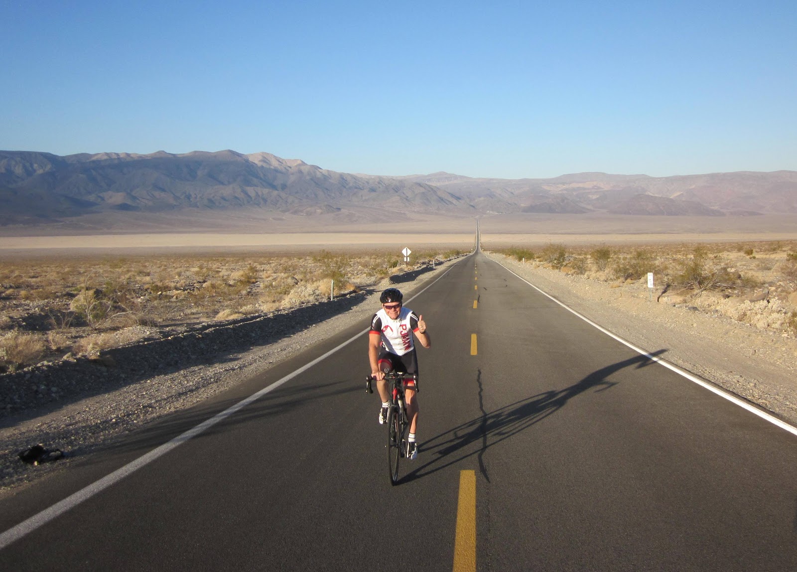 Cycling California top bike climbs - Towne Pass, Death Valley - cyclists on bike on road with long straight road and mountains behind