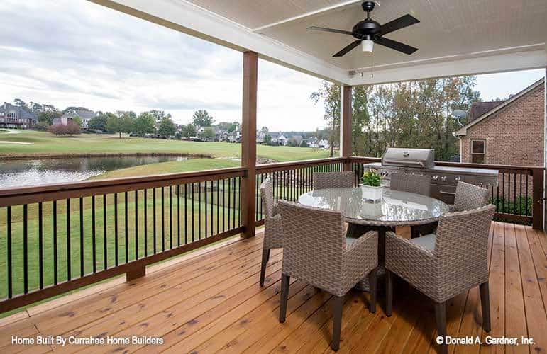 The covered porch offers a round dining set, a bbq grill, and a breathtaking view of the surrounding landscape.