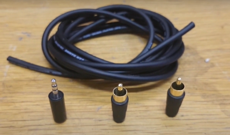 Coiled audio cable with a 3.5mm connector and two RCA connectors placed on a wooden surface. 