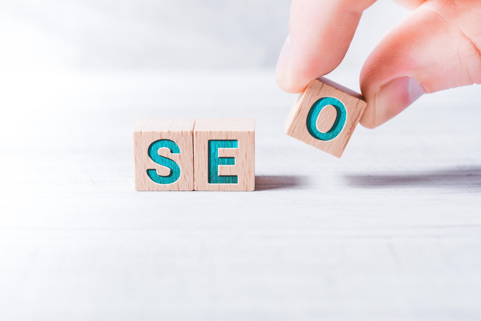 Word “SEO” on wooden blocks being moved by a hand.