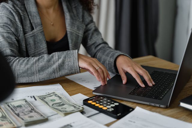 Person counting money and writing on keyboard